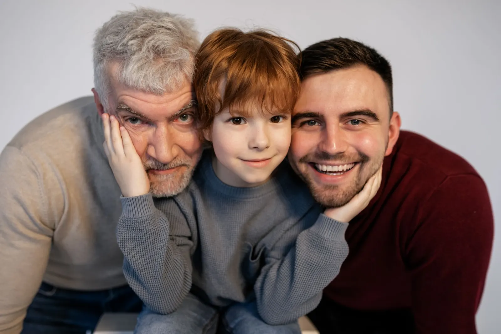 A grandfather, his son and his grandson smiling cheek to cheek