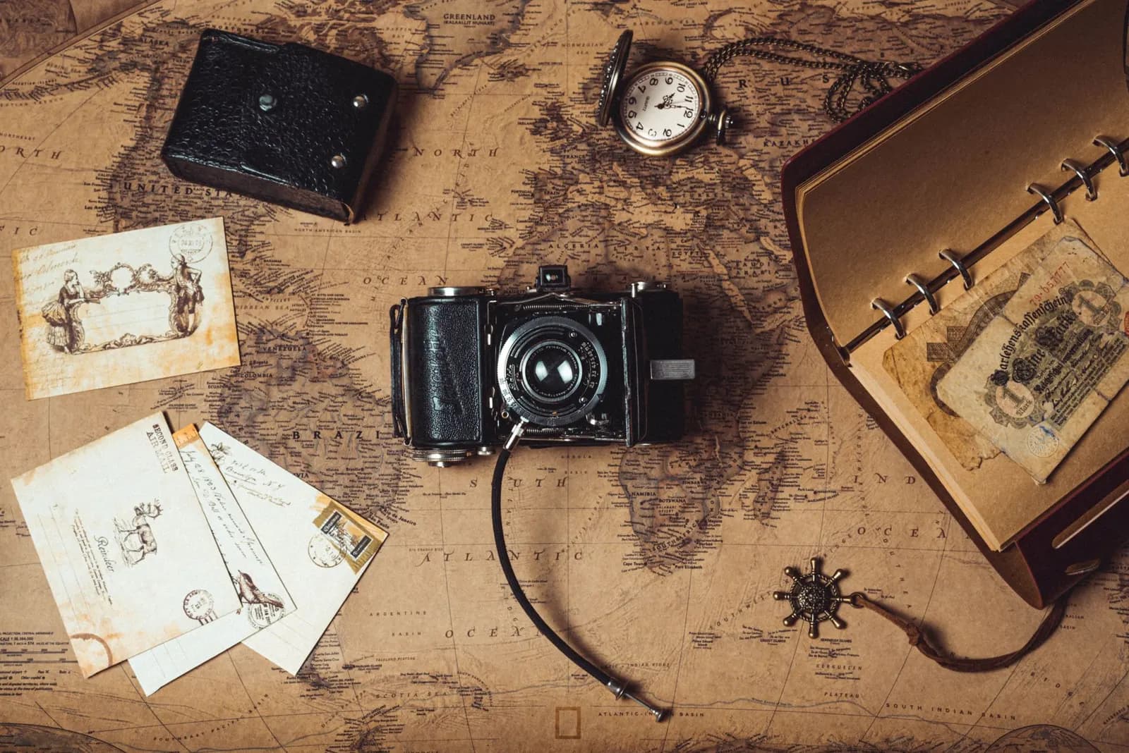An old map with a vintage camera, a journal and old photographs