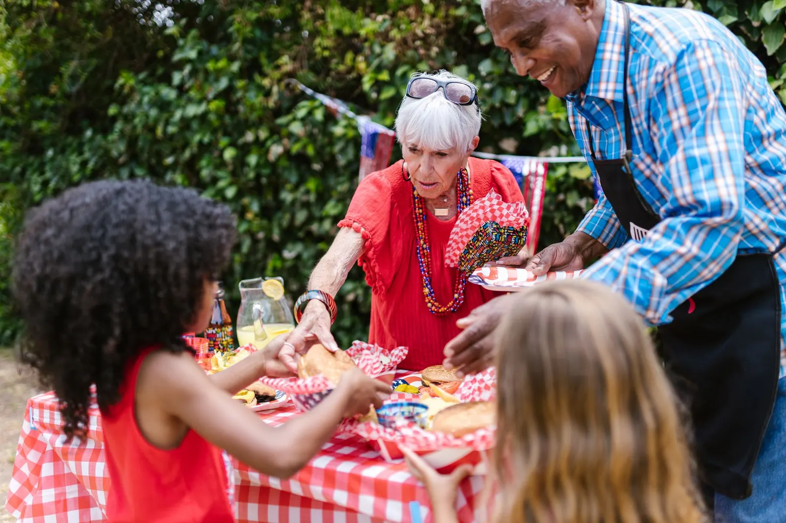 Grandparents serving food to their grandchildren at an outdoor picnic table