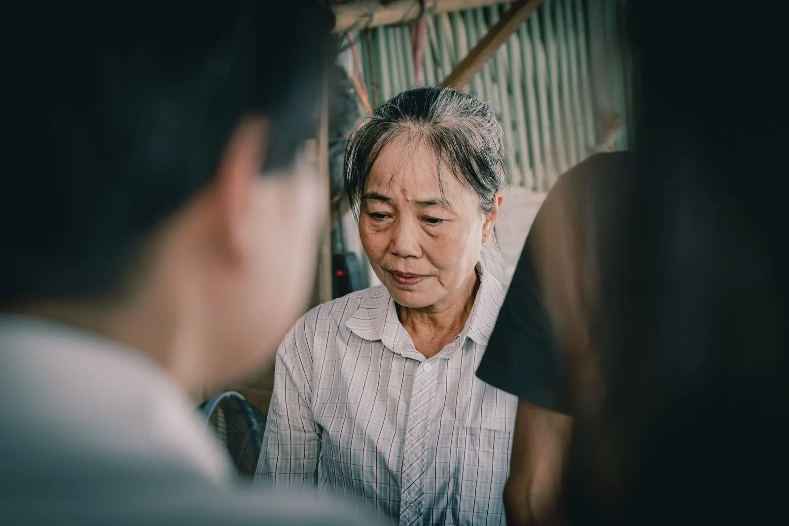 An older woman speaking thoughtfully to someone across the table