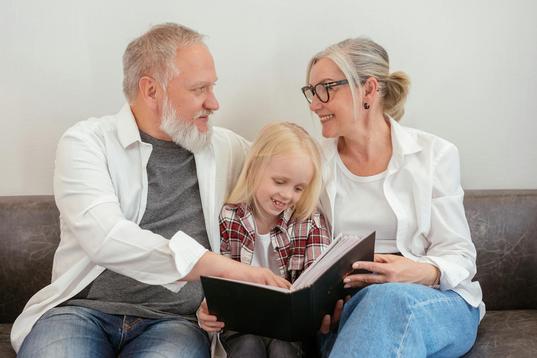 Grandparents and a child looking through a family photo album before creating a private family tree online