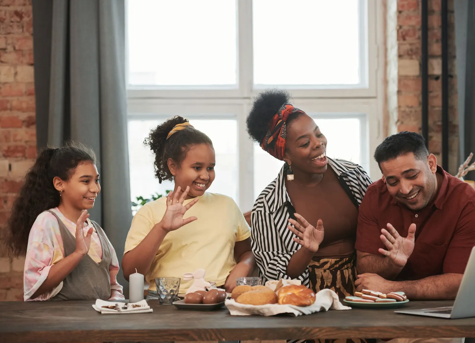 A family at the breakfast table waving to relatives on a video call