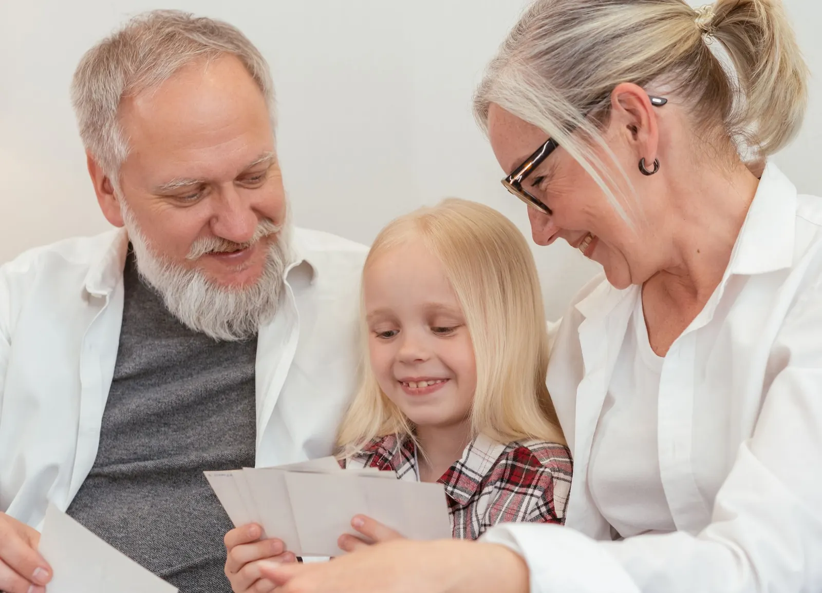 A girl and her grandparents smiling over a handful of printed photographs