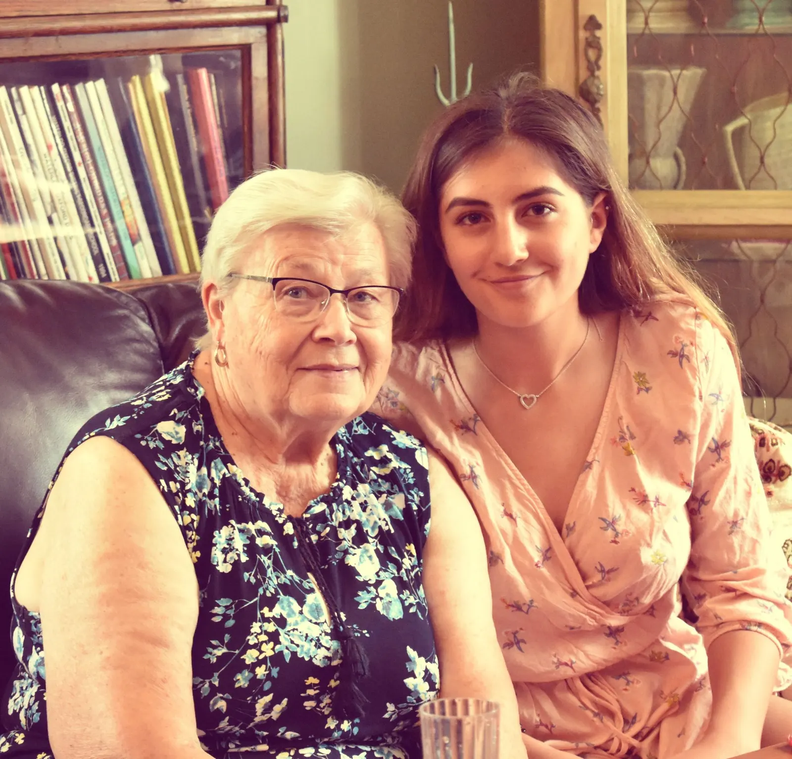 A grandmother and her granddaughter smiling together at home